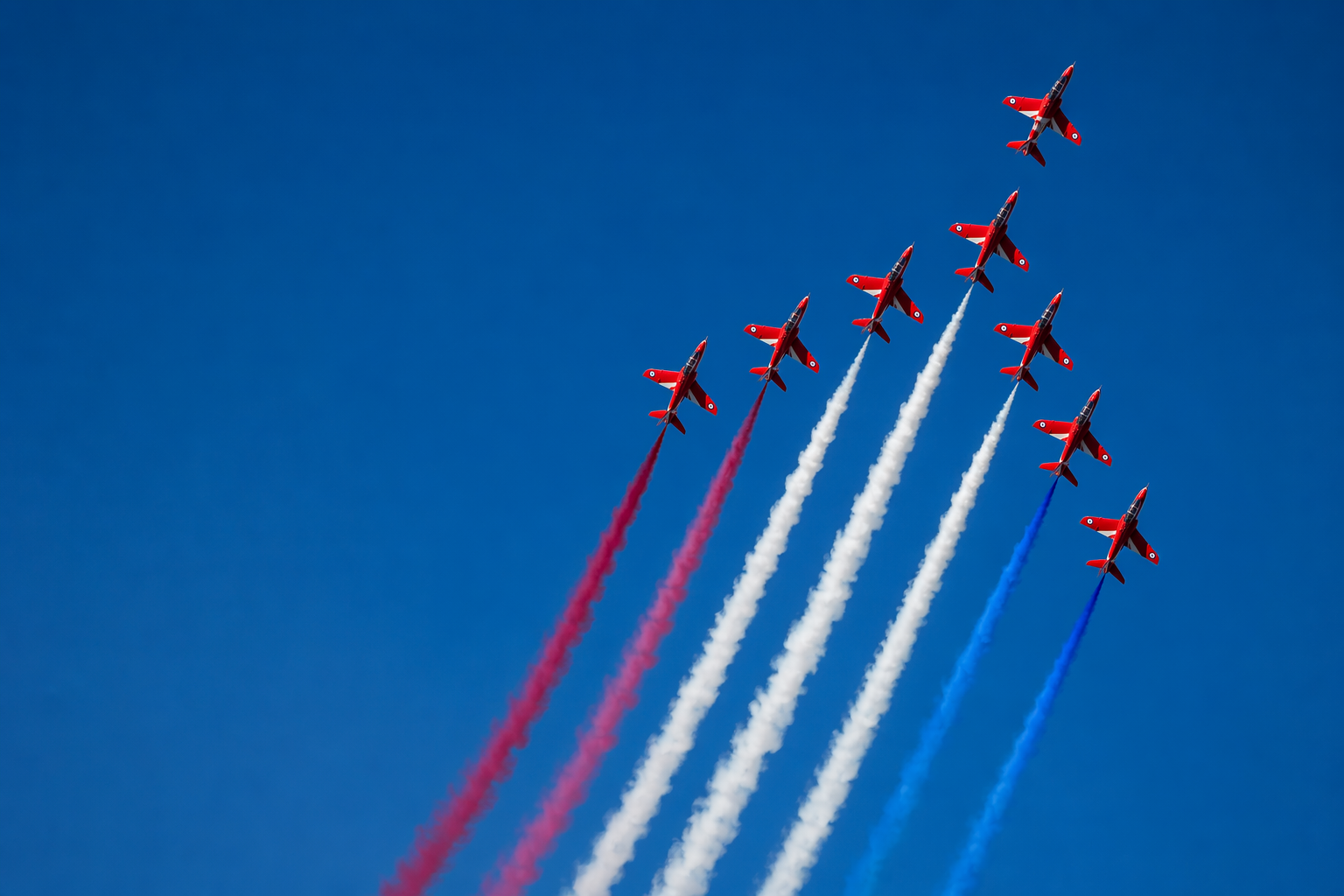 The Red Arrows flying in formation, trailing red, white, and blue smoke